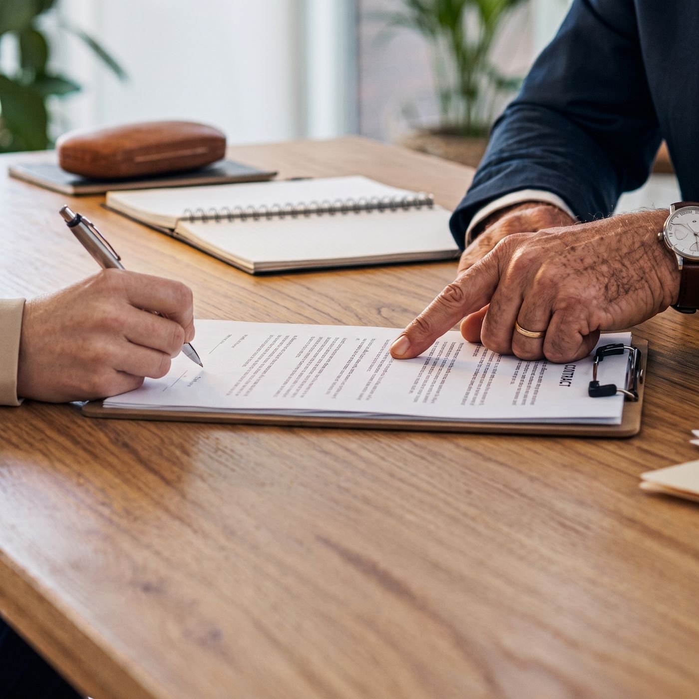 Two professionals reviewing and signing a contract at a wooden desk